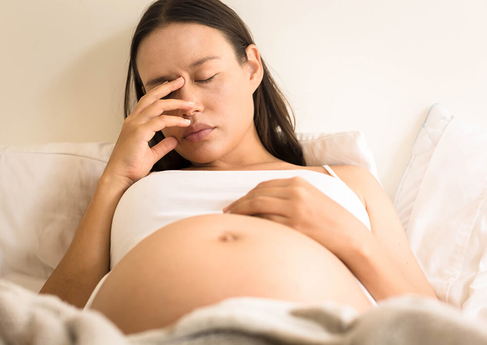 Pregnant lady holding belly with a pained expression
